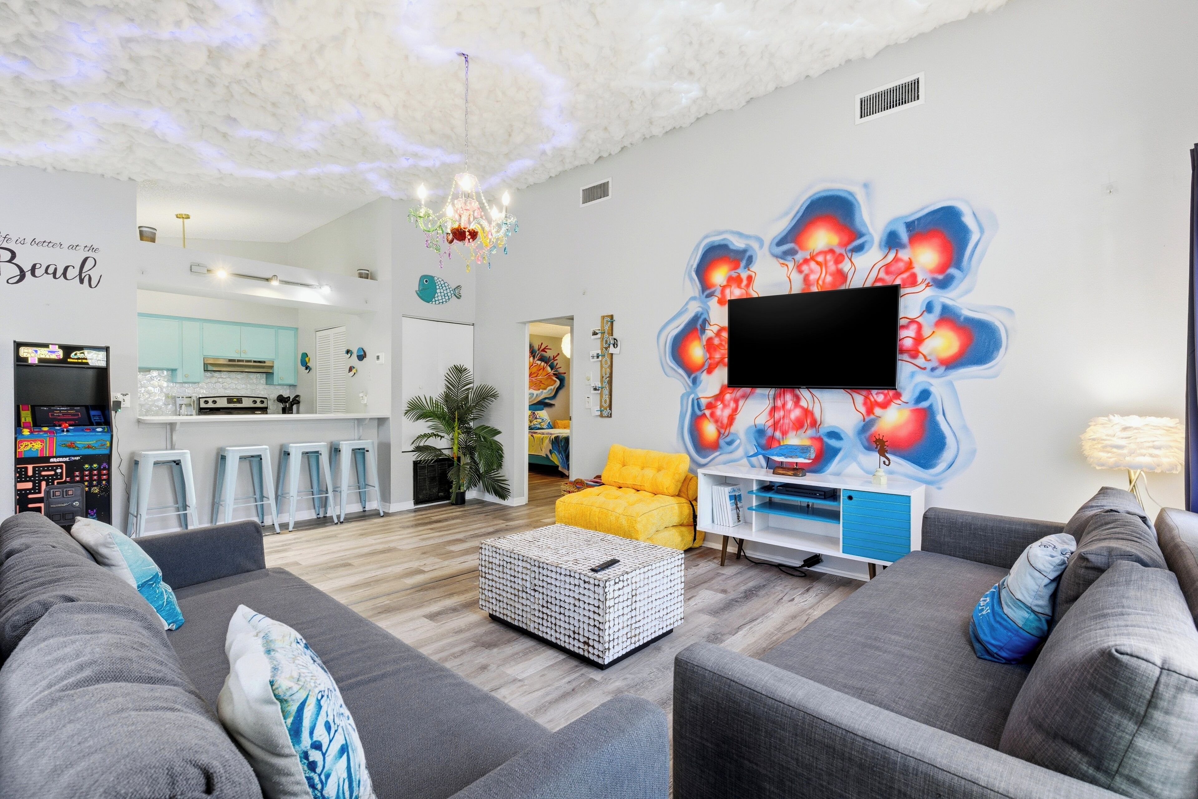 A modern living room with grey sofas, a white coffee table, and a vibrant wall mural.