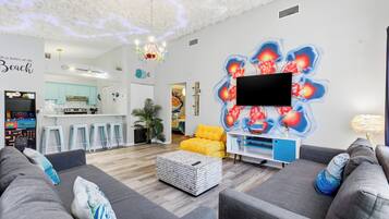 A modern living room with grey sofas, a white coffee table, and a vibrant wall mural.