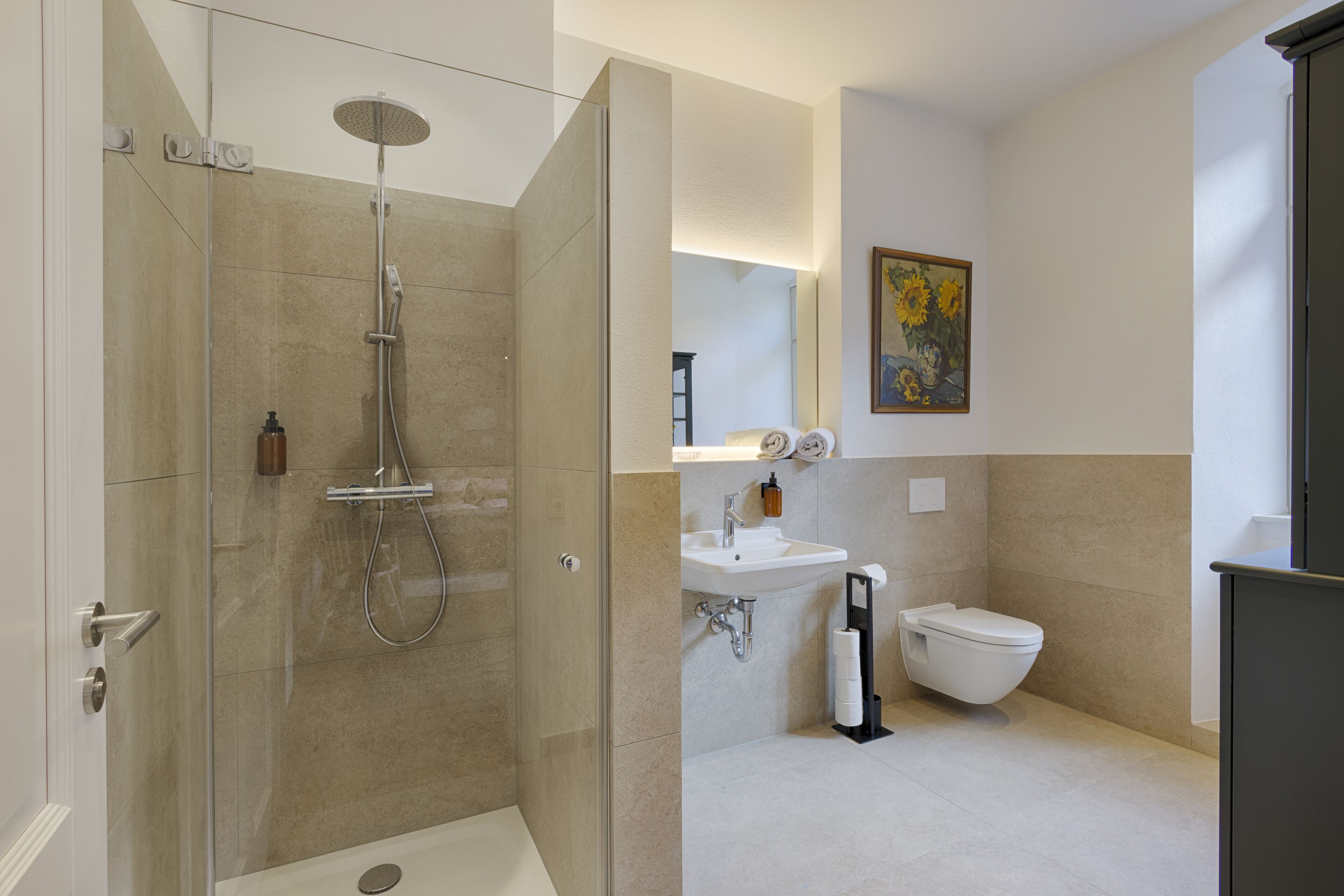 Ein modernes Badezimmer mit einer gläsernen Duschkabine, einem Waschbecken und einer Toilette.