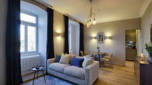 A modern living room with a sofa, a coffee table, and a dining area. - homie stay am schloss (Würzburg)
