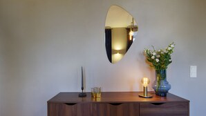A wooden dresser with a mirror, a vase with flowers, and a lamp. - homie stay am schloss (Würzburg)