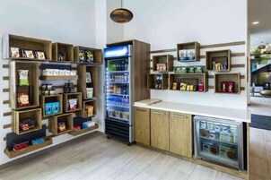 A kitchenette with wooden shelves, a refrigerator, and a small freezer.