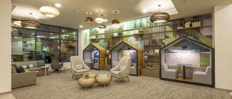 A modern lobby with comfortable seating, a fireplace, and a large window overlooking the city.