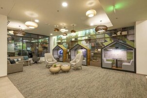 A modern lobby with comfortable seating, a fireplace, and a large window overlooking the city.