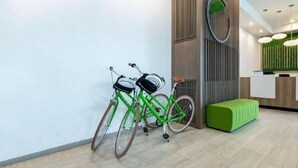 Zona de recepción con un mostrador de madera, dos bicicletas y un banco verde.