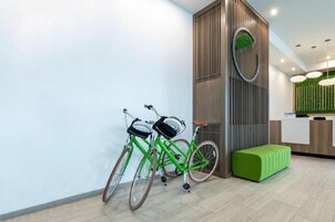 A reception area with a wooden reception desk, two bicycles, and a green bench.