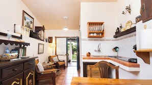 Une cuisine chaleureuse avec une table et des chaises en bois, un coin repas avec un canapé et une vue sur le jardin.