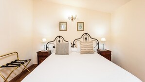 Un lit bien fait avec deux oreillers, une table de chevet avec une lampe et un cadre photo accroché au mur.
