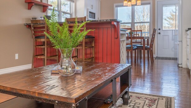 Une cuisine avec une table en bois, des touches de couleur rouge et une plante en guise de décoration centrale.