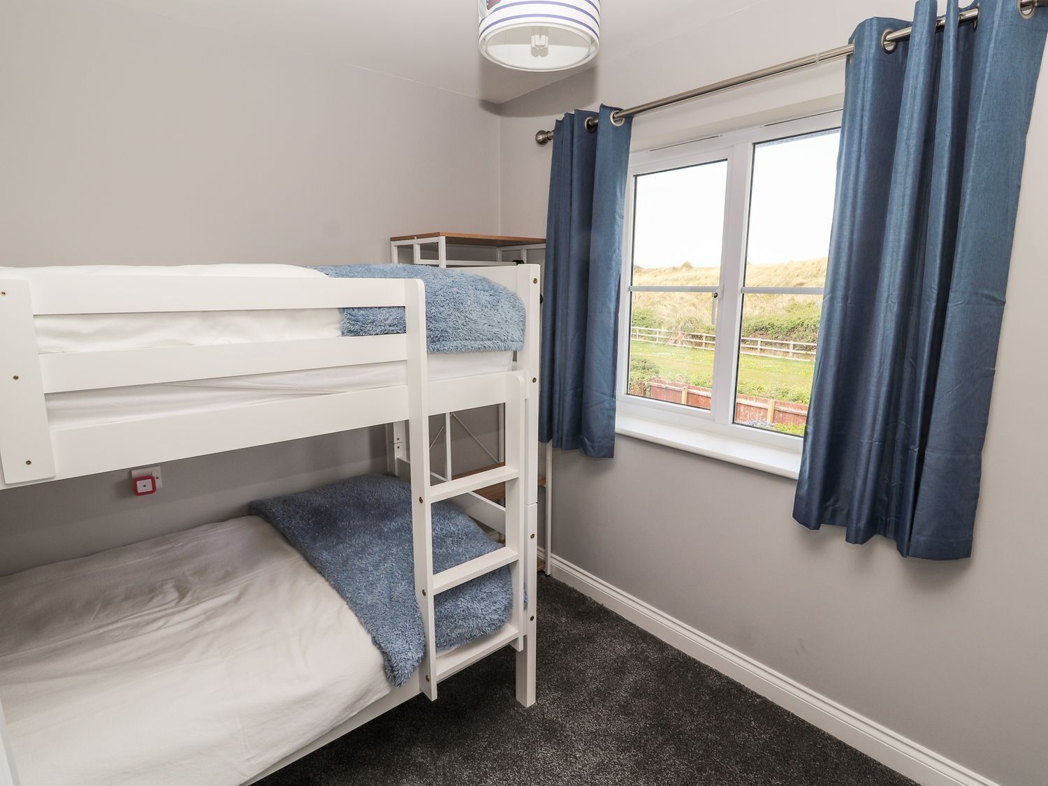 A bunk bed room with a window and curtains.