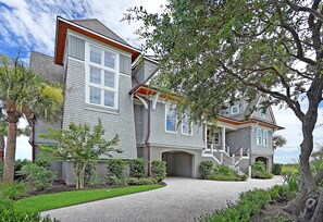 Stunning two-story home with a symmetrical facade, featuring a covered front porch and beautifully maintained gardens.