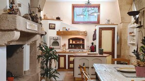 A kitchen with a stone wall, wooden cabinets, a built-in oven, and a dining area with a table and chairs.