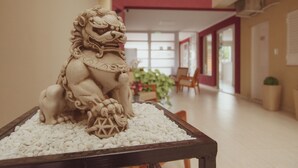 A lion statue on a table in a hallway with a red wall and windows. - Hotel Tonight (Salta)