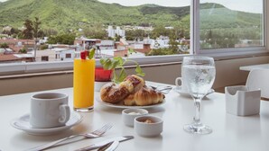 A breakfast table with croissants, a glass of water, and a glass of orange juice. - Hotel Tonight (Salta)