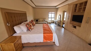 Un dormitorio con una cama grande, cabecera de madera, televisor y armario.