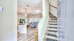 A modern interior with a staircase, a living area with a sofa, and a kitchen area.