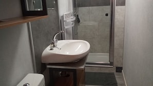 Une petite salle de bain comprenant des toilettes, un lavabo et une douche.