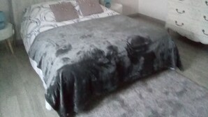 Une chambre à coucher avec un lit, une commode, une décoration en forme de cœur accrochée au mur et un tableau.