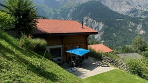 A wooden cabin with a red-tiled roof, a patio with outdoor furniture, and a view of mountains. - Chalet - Calm, comfort and splendid view (Mayens de chamoson)