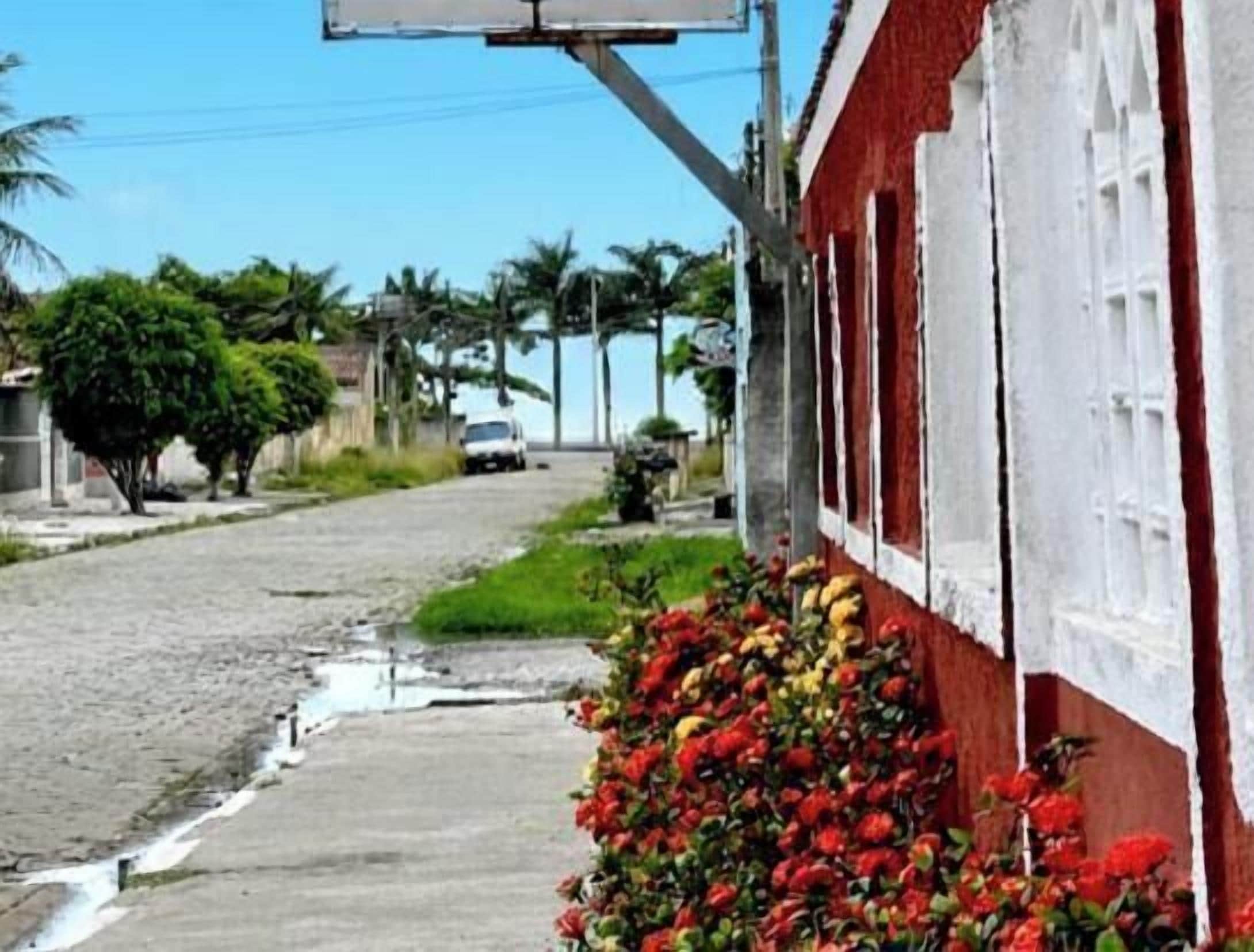 A street with a red building, a white fence, and a flower bed.