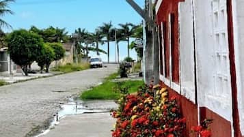 A street with a red building, a white fence, and a flower bed.