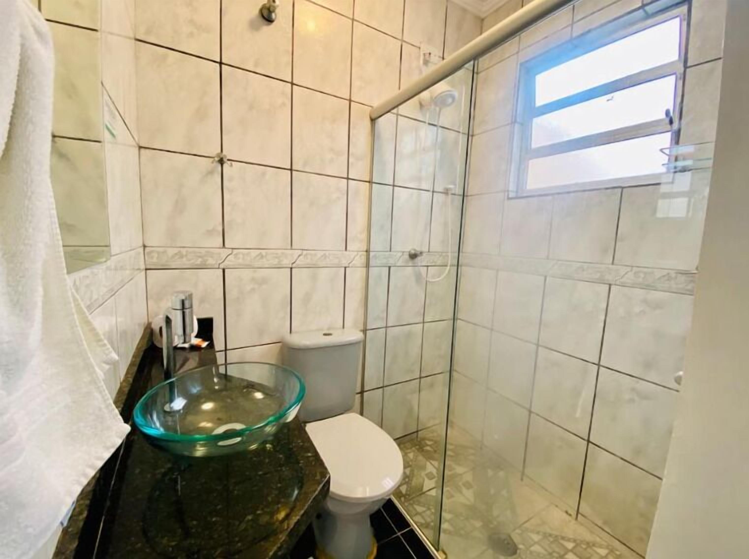 Een badkamer met een wastafel van glas, een toilet en een douchecabine.