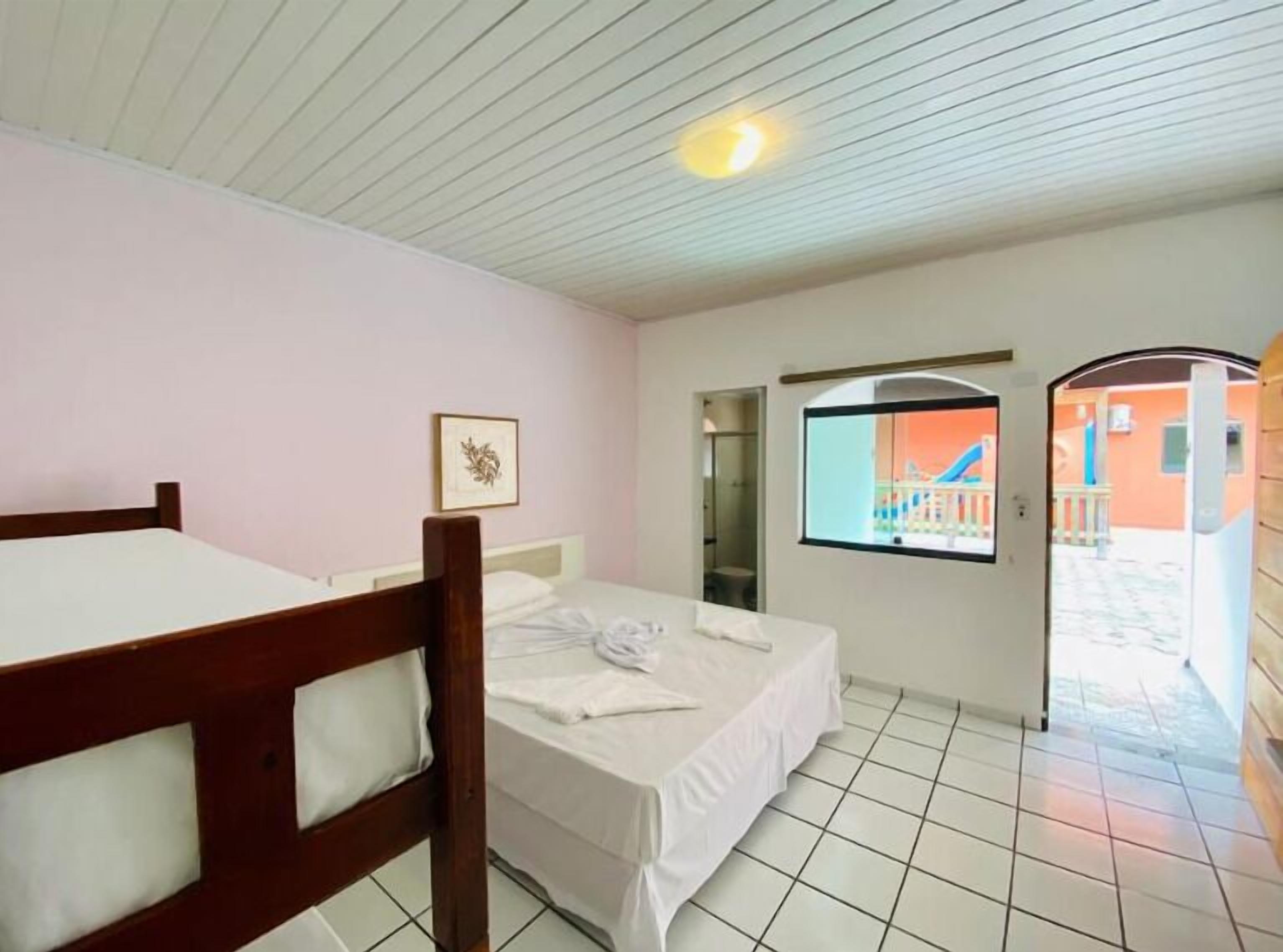 A hotel room with two beds, a bathroom, and a view of the outside.