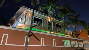 A two-story building with a balcony, surrounded by palm trees. - Pousada Porto do Rio Praia (Caraguatatuba)