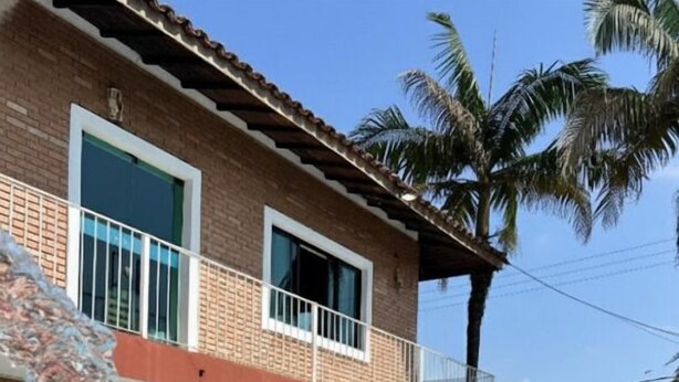 A two-story house with a swimming pool, a balcony, and palm trees. - Pousada Porto do Rio Praia (Caraguatatuba)