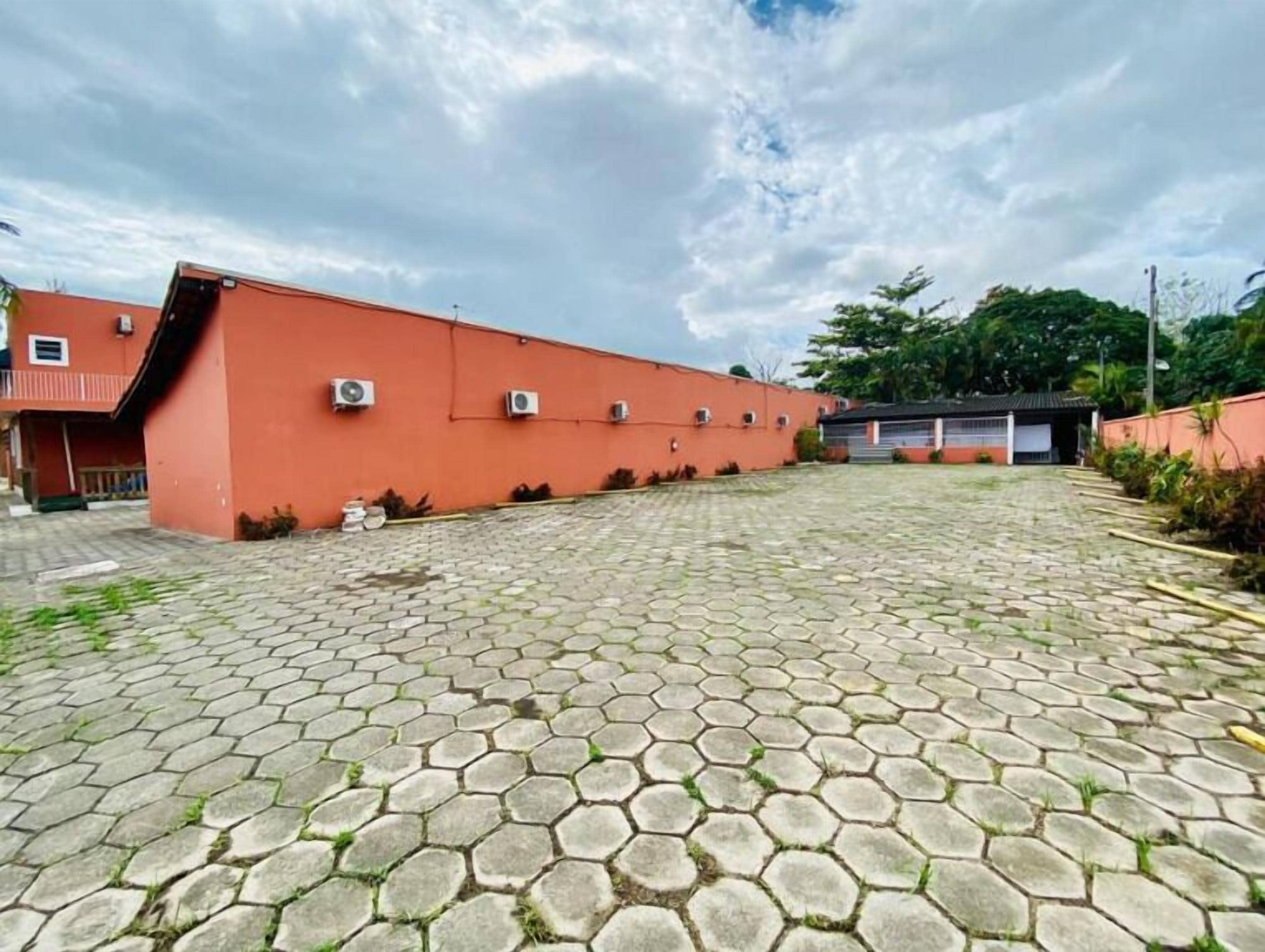 A paved courtyard with hexagonal tiles, surrounded by buildings with air conditioning units.