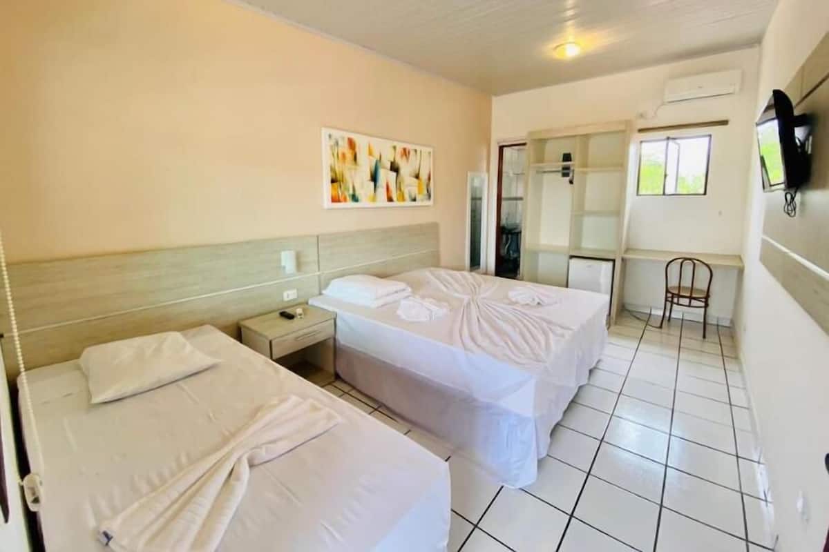A hotel room with two beds, a shower area, and a small seating area.