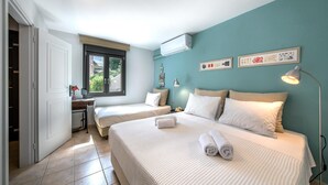 Ein Schlafzimmer mit zwei Betten, einem Schreibtisch, einem Fenster und einer Wand-Klimaanlage.