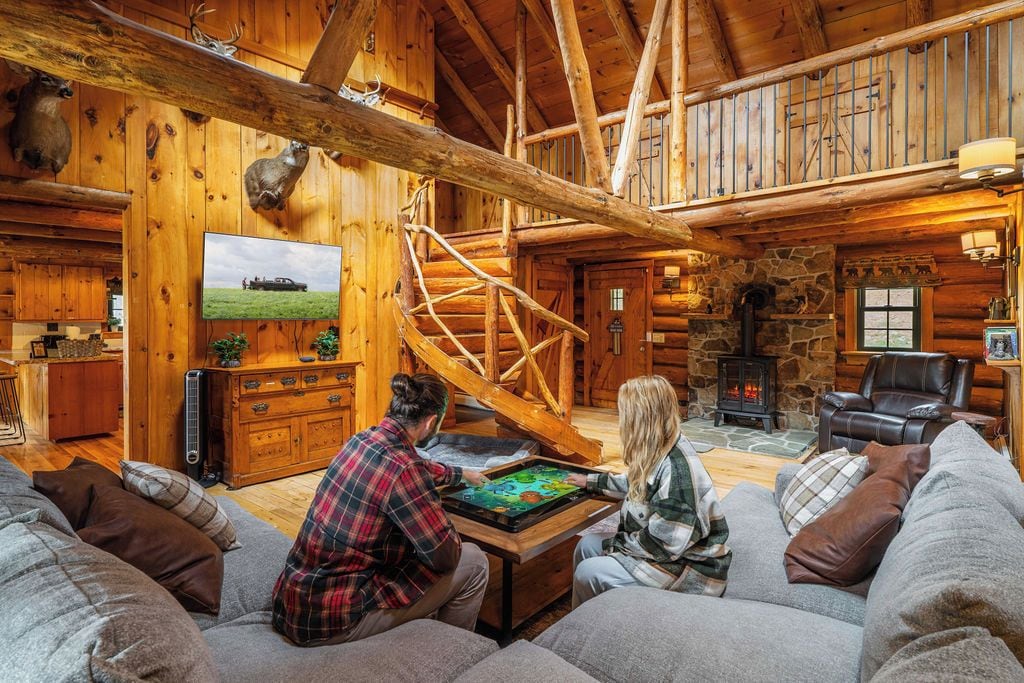 Een gezellig houten blokhutinterieur met een open haard, houten wanden en een wenteltrap.