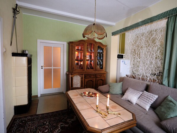 Un salon avec un canapé, une table basse ornée de bougies, un meuble en bois et un mur à motifs.