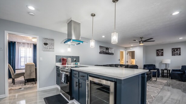 A modern kitchen with a central island, built-in oven, and pendant lighting. - Super Luxurious House (Atlanta)