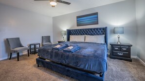 A bedroom with a large bed, two bedside tables, a ceiling fan, and a wall-mounted painting. - Super Luxurious House (Atlanta)