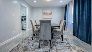 A dining area with a marble floor, a chandelier, a painting on the wall, and a view of the kitchen. - Super Luxurious House (Atlanta)