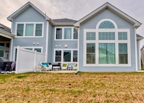 A two-story house with a covered patio, a fenced yard, and a large window on the front.