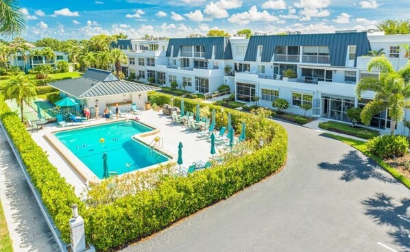 A resort with a swimming pool, lounge chairs, and a well-maintained garden.