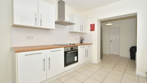 A kitchen with white cabinets, a wooden countertop, and a black oven.