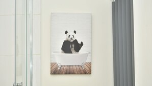 A bathroom with a glass shower enclosure, a white bathtub, and a wooden floor.