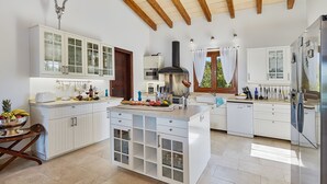 Une cuisine spacieuse avec des meubles blancs, un îlot central et un four encastré.