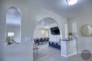 A modern living room with a TV, dining area, and a small seating nook.