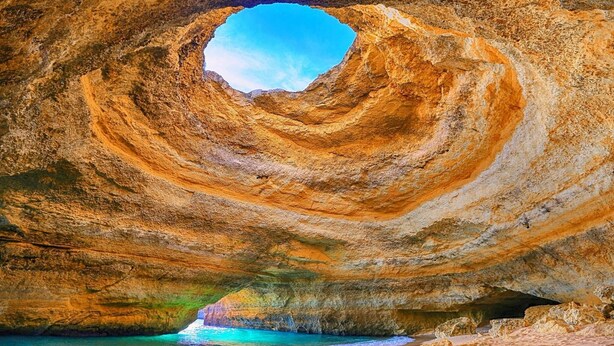 A natural rock formation with a circular opening, a beach in front, and a clear sky. - Blue Sky Condo with Ocean&Pool view by Be Cherish (Albufeira)