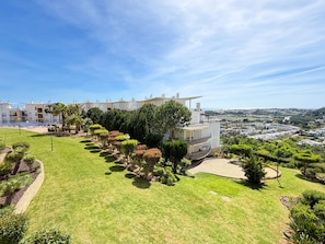 A residential building with a pool, surrounded by well-maintained gardens and a clear view of the cityscape.
