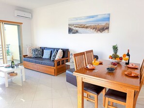 Ein modernes Wohnzimmer mit einer Couch, einem Esstisch und einem Gemälde an der Wand.