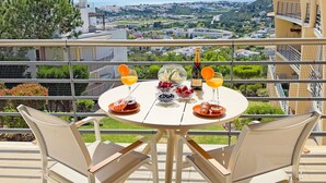 A round table with chairs on a balcony overlooking a scenic view. - Blue Sky Condo with Ocean&Pool view by Be Cherish (Albufeira)