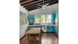 A kitchen with teal cabinets, a wooden table, and a ceiling fan. - Villa Valeria - An eco hideaway with all the modern luxuries (Cabo Rojo)
