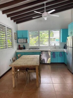 A kitchen with teal cabinets, a wooden table, and a ceiling fan.