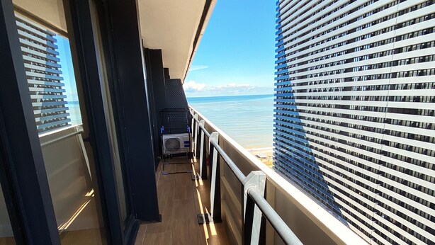 A corridor with a view of the sea and a building with horizontal windows. - Orbi City/Two Rooms Apt./27 Floor/Sea - Mout. View (Batumi)